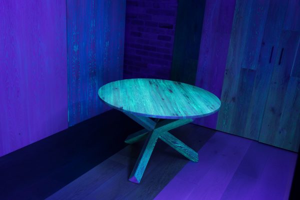 image of the glowing solid oak dining table with UVA lighting that charges the table to make the grain stand out.